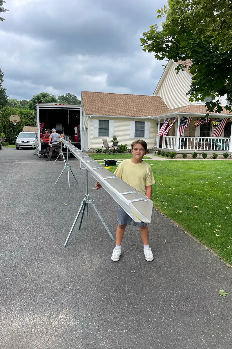 Next-generation Supreme Gutters crew member with a freshly fabricated seamless gutter on-site in Western MA